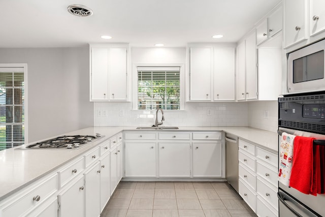 kitchen with sink, light tile patterned floors, gas stovetop, oven, and white cabinets