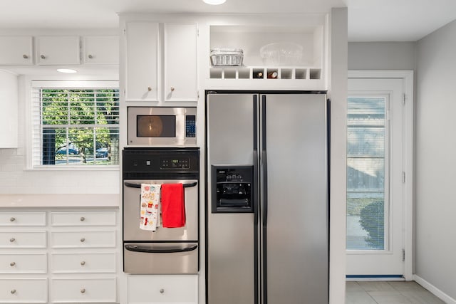 kitchen featuring backsplash, white cabinetry, light tile patterned flooring, and stainless steel appliances