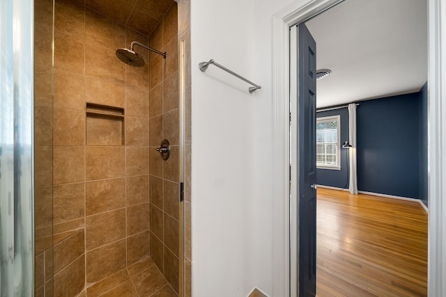 bathroom with hardwood / wood-style flooring and tiled shower