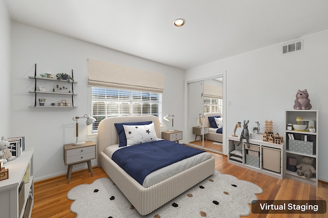 bedroom with light hardwood / wood-style floors, multiple windows, and a closet