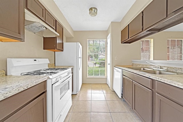 kitchen with light tile patterned floors, a textured ceiling, sink, and white appliances