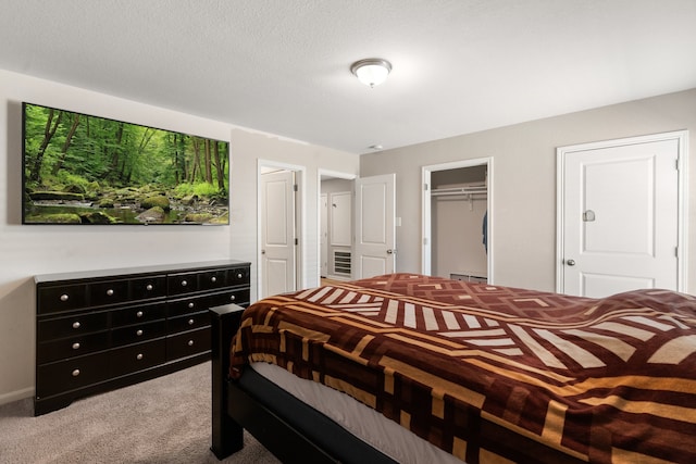 carpeted bedroom featuring a spacious closet, baseboard heating, a textured ceiling, and a closet