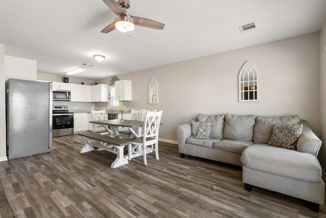 living room featuring ceiling fan and dark wood-type flooring