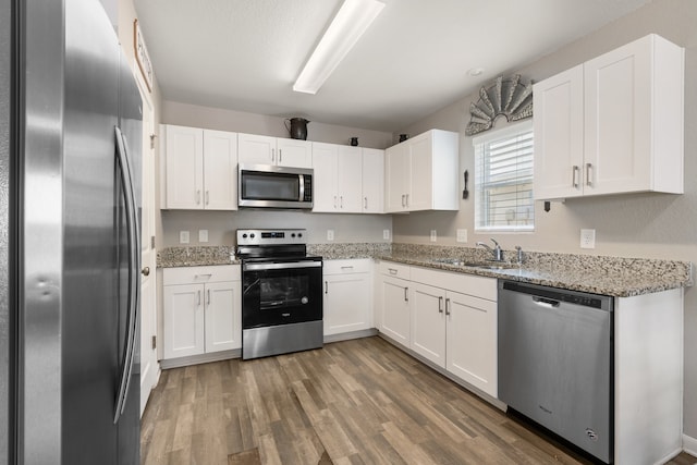 kitchen featuring white cabinetry, stainless steel appliances, and light stone counters