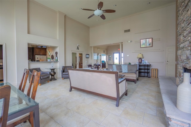 living room featuring ceiling fan, a towering ceiling, and ornamental molding