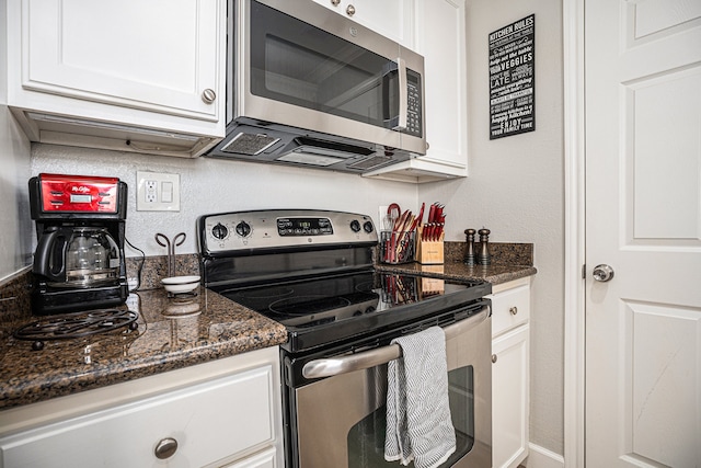 kitchen with white cabinets, stainless steel appliances, and dark stone countertops