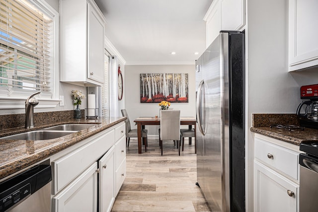 kitchen featuring white cabinets, sink, light hardwood / wood-style flooring, dark stone countertops, and appliances with stainless steel finishes