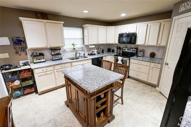 kitchen with light stone counters, a center island, tasteful backsplash, sink, and black appliances