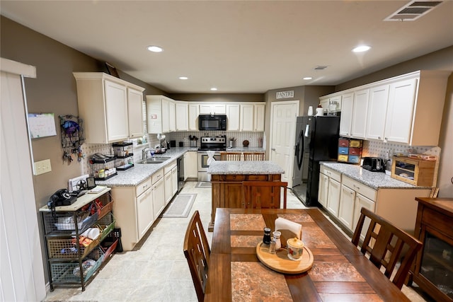 kitchen with sink, black appliances, white cabinetry, and backsplash