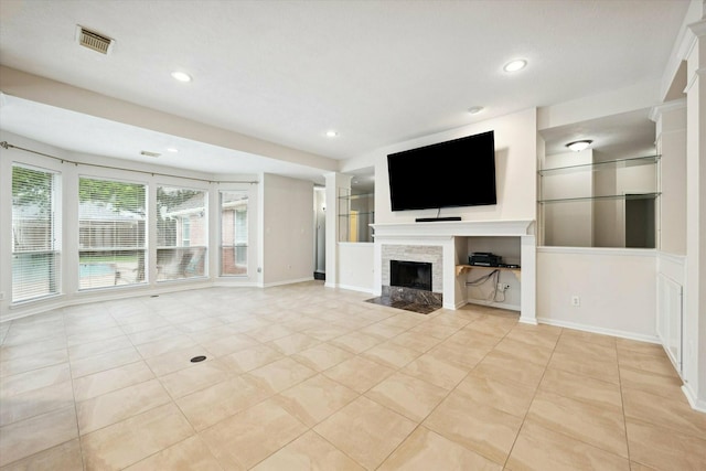 unfurnished living room with light tile patterned floors and a stone fireplace