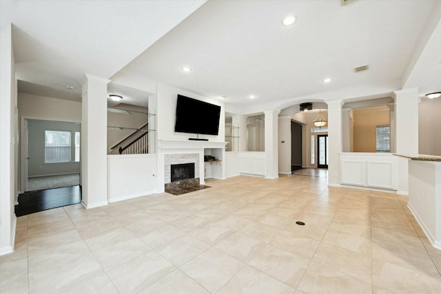 unfurnished living room with built in shelves, a premium fireplace, and light tile patterned floors