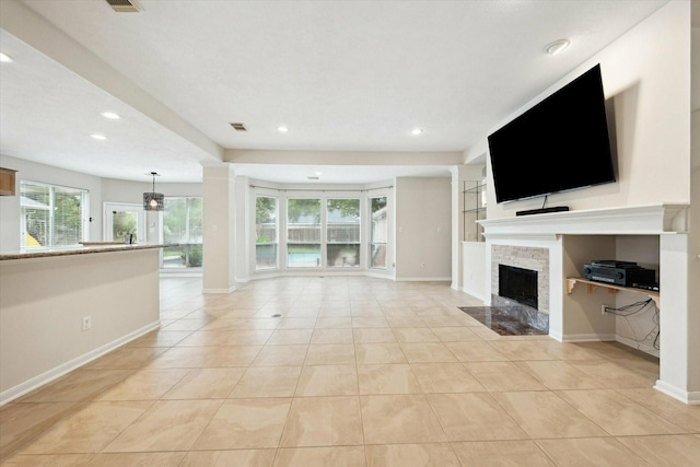 unfurnished living room featuring built in shelves, a stone fireplace, and light tile patterned floors