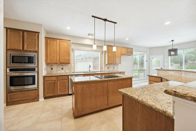 kitchen featuring decorative backsplash, light stone counters, stainless steel appliances, pendant lighting, and a kitchen island