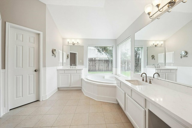 bathroom with tile patterned floors, a bathing tub, vanity, and vaulted ceiling