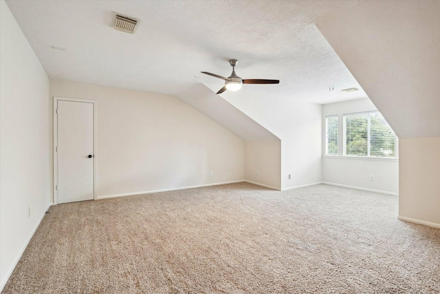 additional living space featuring ceiling fan, a textured ceiling, light carpet, and vaulted ceiling