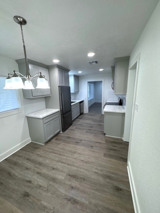 kitchen featuring stainless steel fridge, gray cabinetry, a textured ceiling, dark hardwood / wood-style floors, and an inviting chandelier