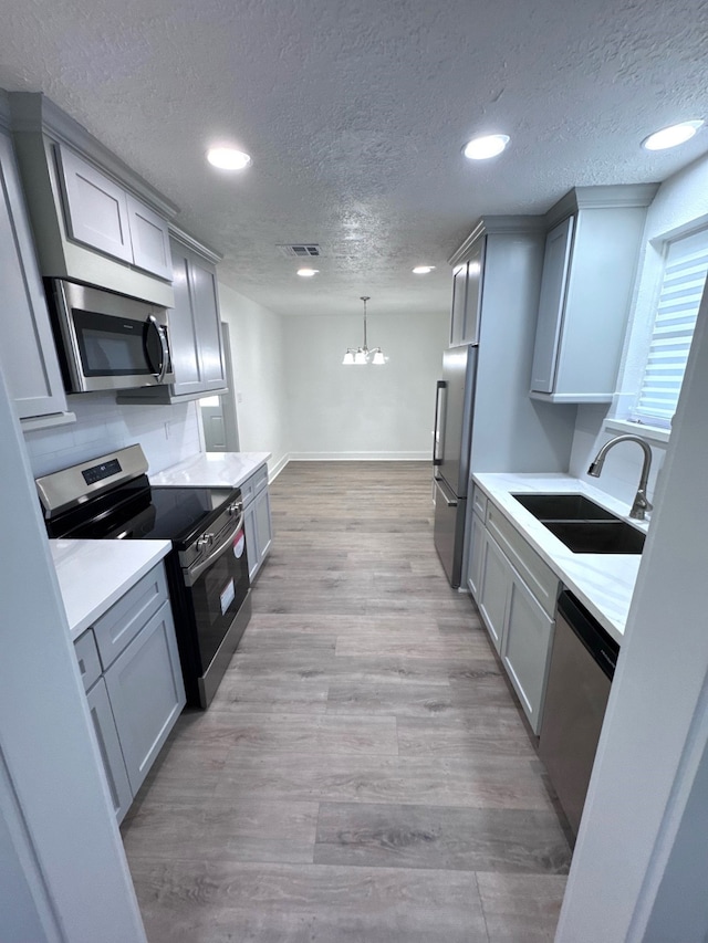 kitchen featuring gray cabinetry, stainless steel appliances, light hardwood / wood-style flooring, and sink