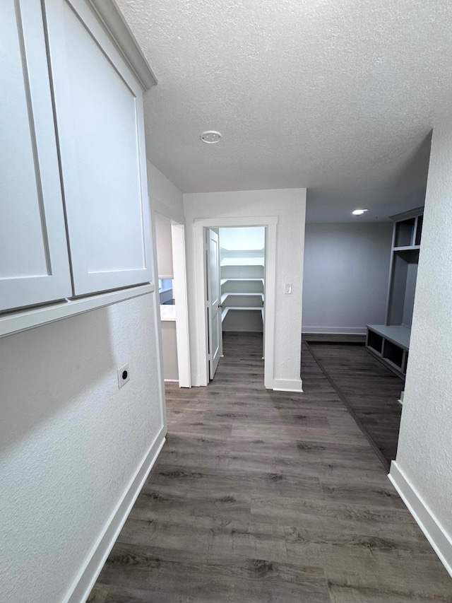 hall with a textured ceiling and dark wood-type flooring