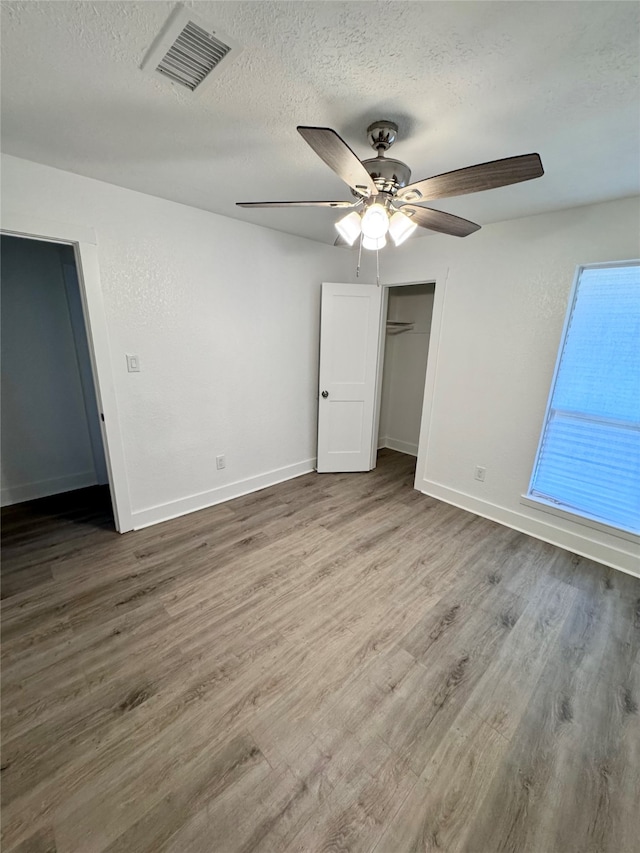 unfurnished bedroom with ceiling fan, a textured ceiling, and hardwood / wood-style floors