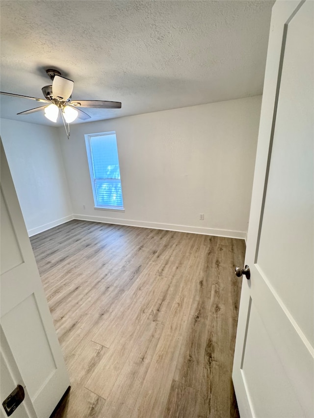 empty room featuring light hardwood / wood-style flooring, ceiling fan, and a textured ceiling