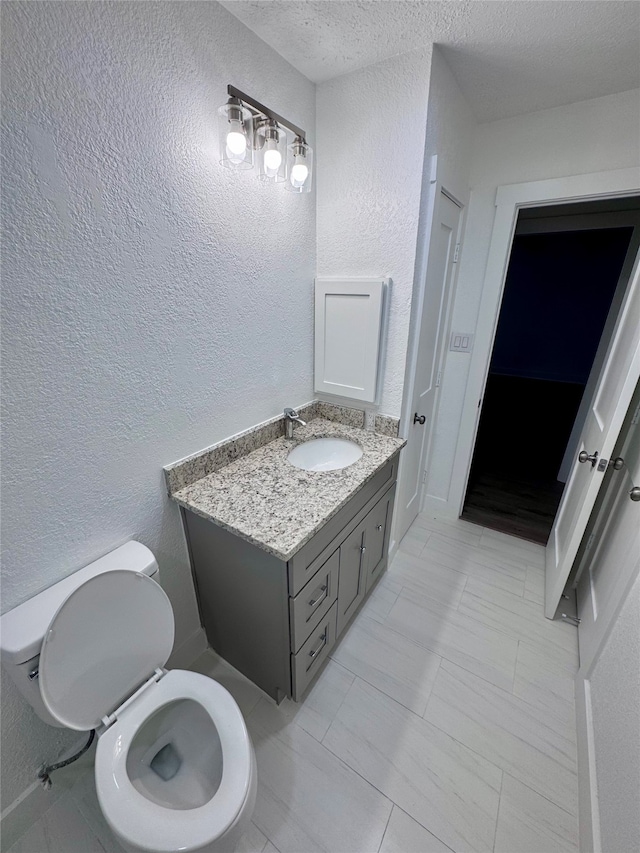 bathroom featuring vanity, toilet, and a textured ceiling