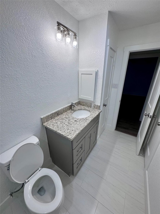 11722 Chadbrook Ln, Houston, TX 77099 - bathroom with a textured wall, toilet, vanity, and a textured ceiling