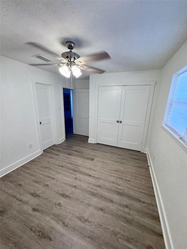 unfurnished bedroom with ceiling fan, hardwood / wood-style flooring, and a textured ceiling