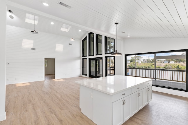 kitchen with high vaulted ceiling, white cabinetry, a center island, and hanging light fixtures