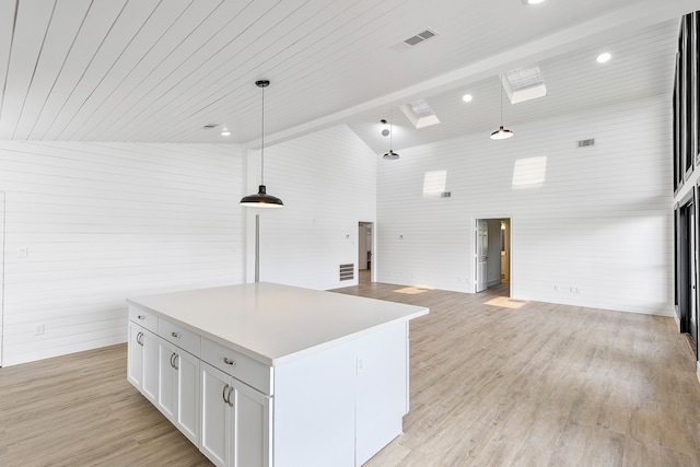 kitchen featuring white cabinets, a kitchen island, decorative light fixtures, high vaulted ceiling, and light hardwood / wood-style floors