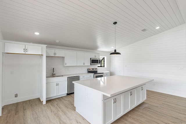 kitchen with pendant lighting, a center island, white cabinets, vaulted ceiling, and appliances with stainless steel finishes