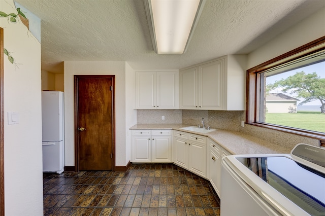 kitchen featuring washer / clothes dryer, sink, white cabinets, white fridge, and a textured ceiling