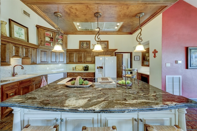 kitchen featuring a kitchen breakfast bar, a large island, sink, crown molding, and white appliances