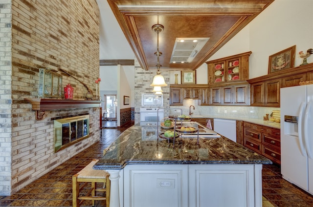 kitchen featuring crown molding, dark stone countertops, decorative light fixtures, and white appliances