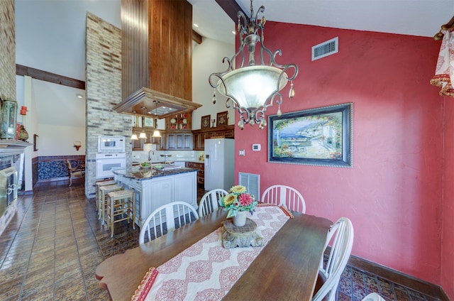 dining space featuring a large fireplace and high vaulted ceiling