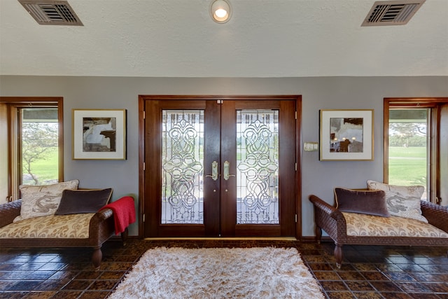 foyer featuring french doors, a textured ceiling, and a healthy amount of sunlight