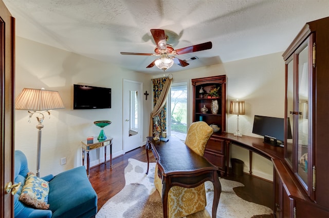 home office featuring built in desk, ceiling fan, a textured ceiling, and dark hardwood / wood-style flooring