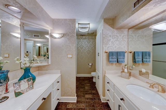 bathroom featuring vanity, a textured ceiling, and toilet