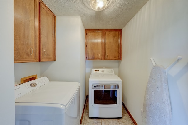 laundry room with washing machine and dryer, light tile patterned flooring, a textured ceiling, and cabinets