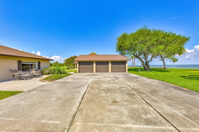 exterior space featuring a water view, an outdoor structure, a lawn, and a garage