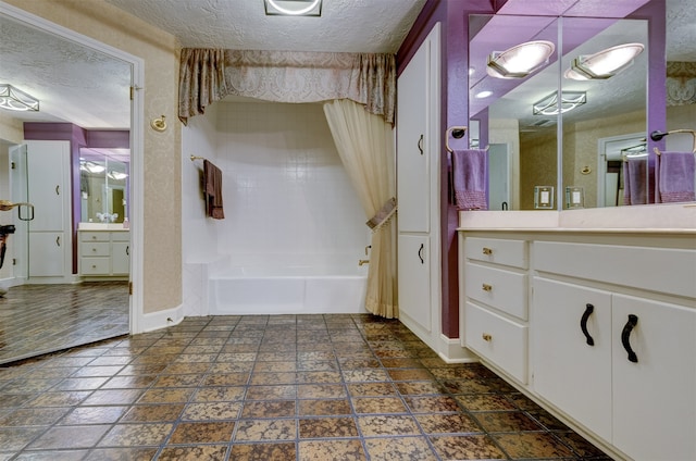 bathroom featuring vanity, a textured ceiling, and washtub / shower combination