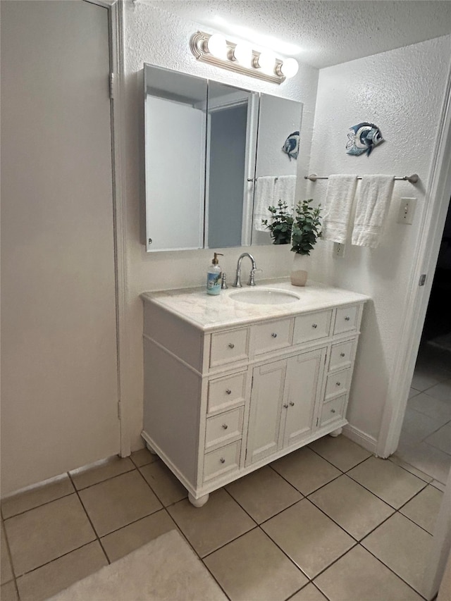 bathroom with tile patterned flooring, a textured ceiling, and vanity