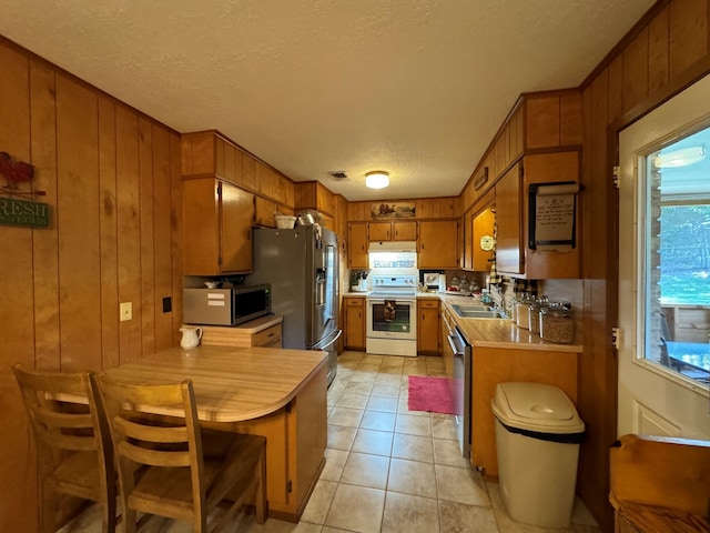 kitchen featuring stainless steel appliances, wood walls, and kitchen peninsula