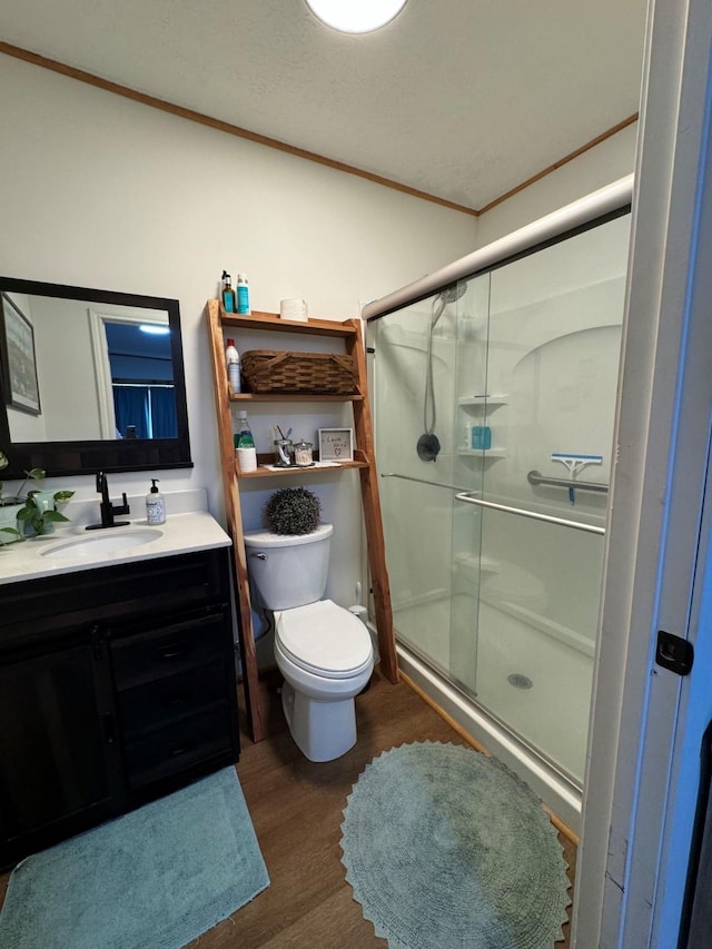full bath with a shower stall, vanity, ornamental molding, and wood finished floors