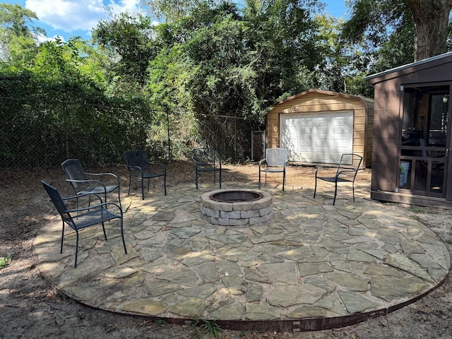 view of patio / terrace featuring a storage shed, fence, a fire pit, and an outdoor structure