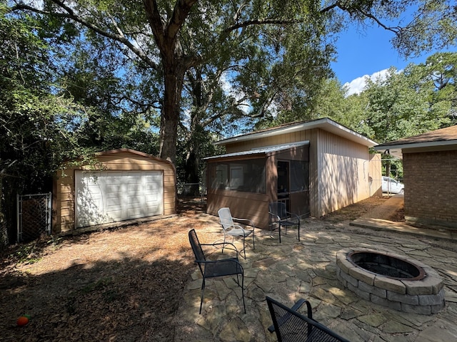 rear view of house with a garage, an outbuilding, a patio area, and an outdoor fire pit