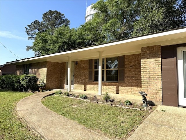 view of front facade featuring brick siding, a front lawn, and covered porch