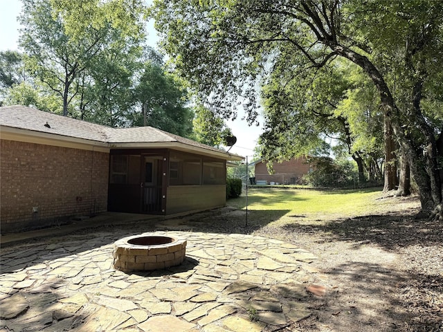 view of patio / terrace featuring an outdoor fire pit, fence, and a sunroom