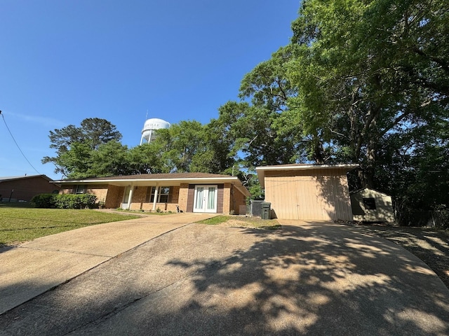 ranch-style home with a shed, an outdoor structure, brick siding, french doors, and driveway