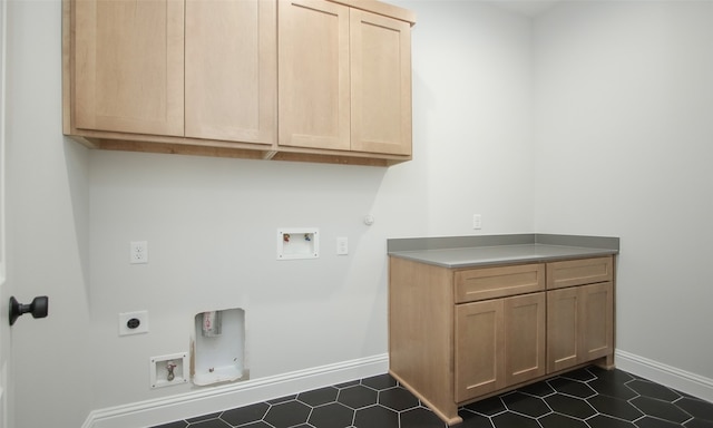 laundry area with gas dryer hookup, electric dryer hookup, dark tile patterned floors, and cabinets