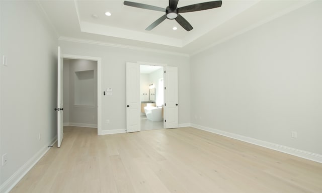 unfurnished bedroom with light wood-type flooring, a tray ceiling, ceiling fan, ensuite bathroom, and ornamental molding